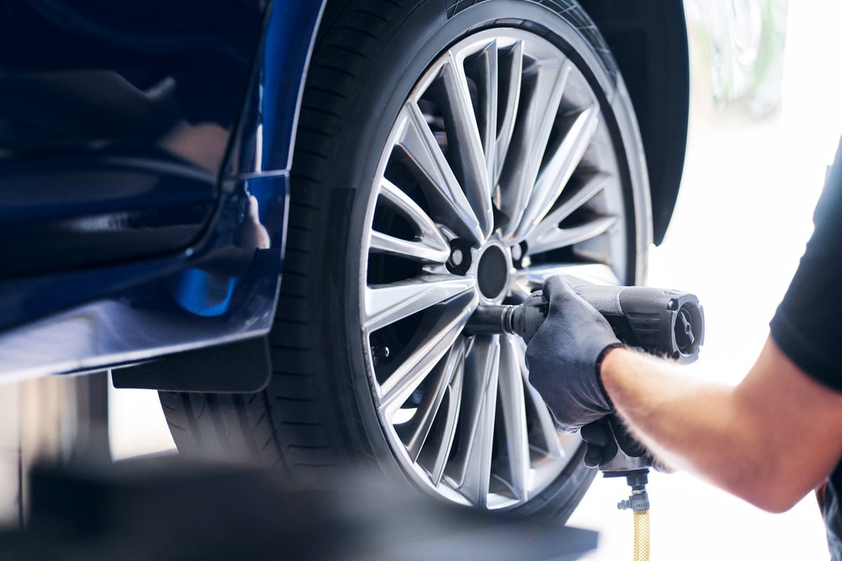 Borracharia trocando o pneu de um carro com pistola pneumática no local